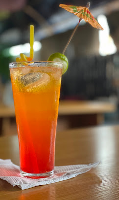 Tall fruit cocktail with umbrella garnish on a wooden table